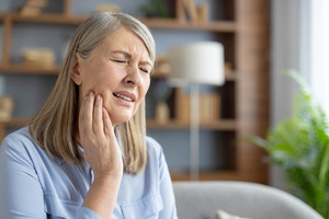 Woman on couch with jaw pain from TMJ disorder