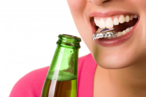 Woman opening a bottle with her teeth